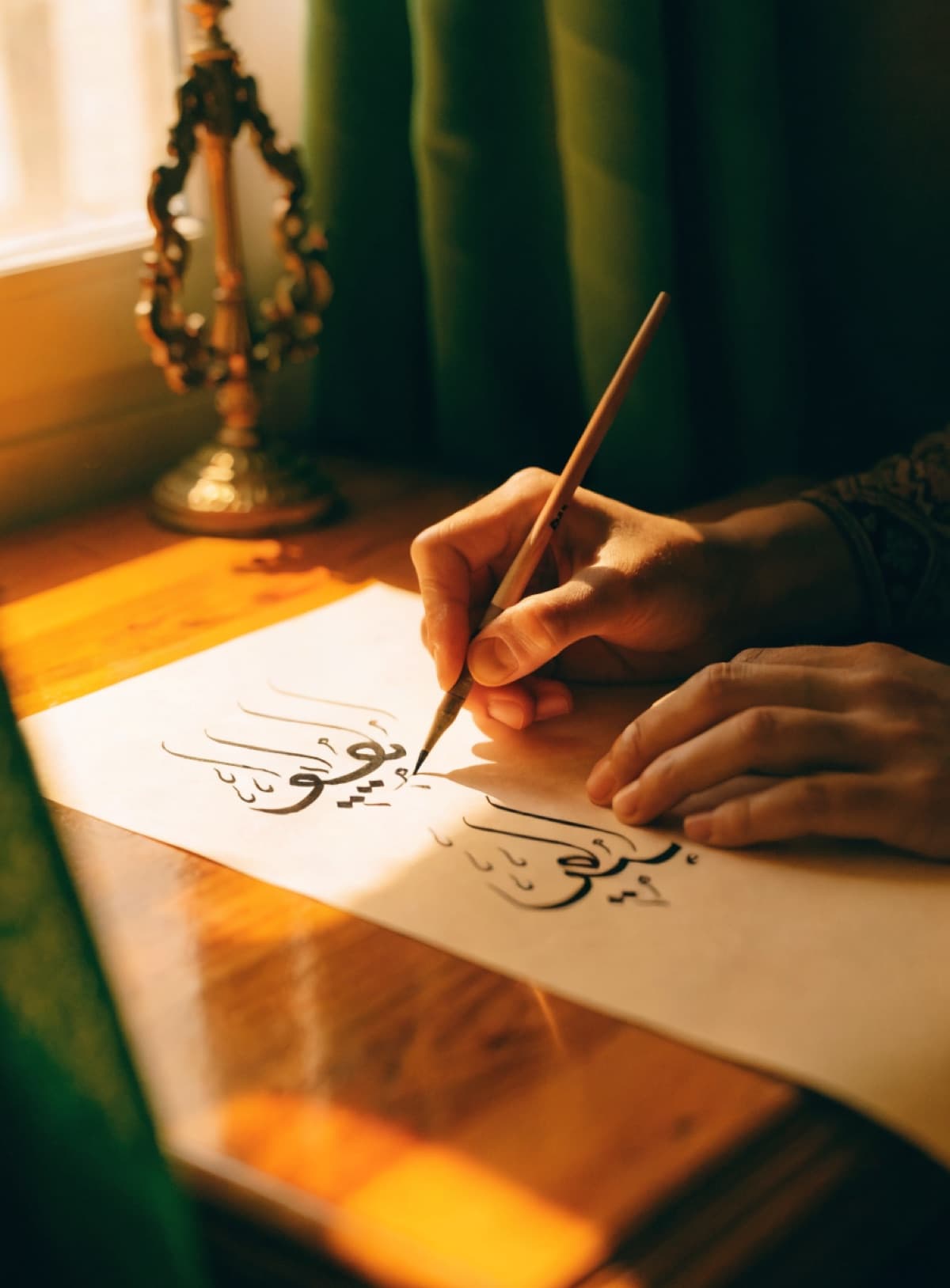 Mains d'un élève écrivant la calligraphie arabe au qalam